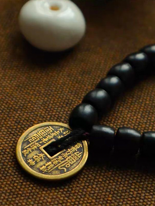 This is an ebony bracelet paired with a Taoist mountain spirit charm, displayed against a woven background.