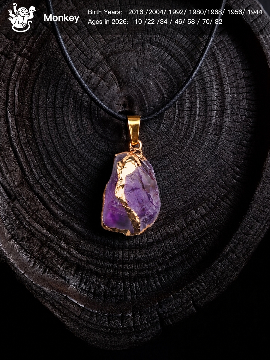 A raw purple amethyst crystal pendant necklace with gold foil accents and a gold bail, displayed on a dark wood slice background. The image includes a 'Monkey' birth chart overlay in the top left corner.