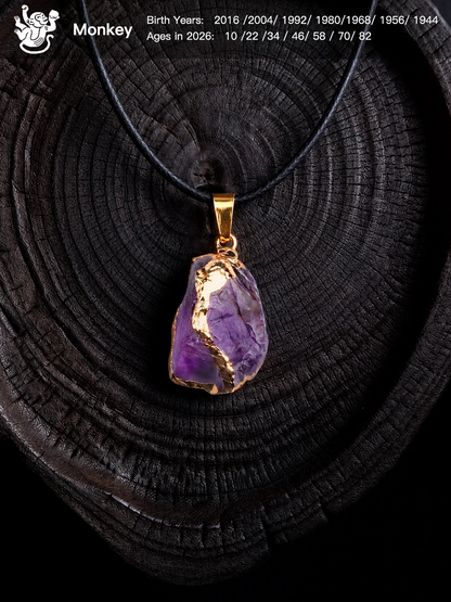 A raw purple amethyst crystal pendant necklace with gold foil accents and a gold bail, displayed on a dark wood slice background. The image includes a 'Monkey' birth chart overlay in the top left corner.