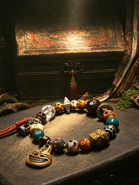 A beaded necklace with a skull pendant and various decorative beads, displayed on a dark wooden surface with a gothic-themed background featuring a chest and draped fabric.