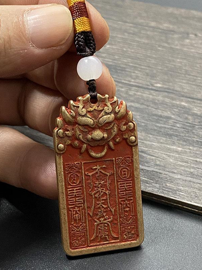 One hand holds a Taoist general's tablet, showing the front side against a wood grain background.