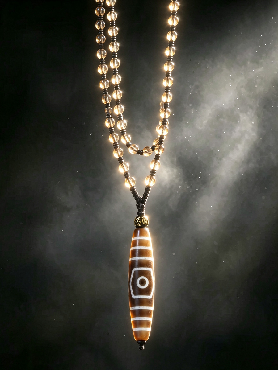 A beaded necklace with a long cylindrical pendant featuring a white eye motif on a brown and white striped background, suspended against a dark smoky backdrop.