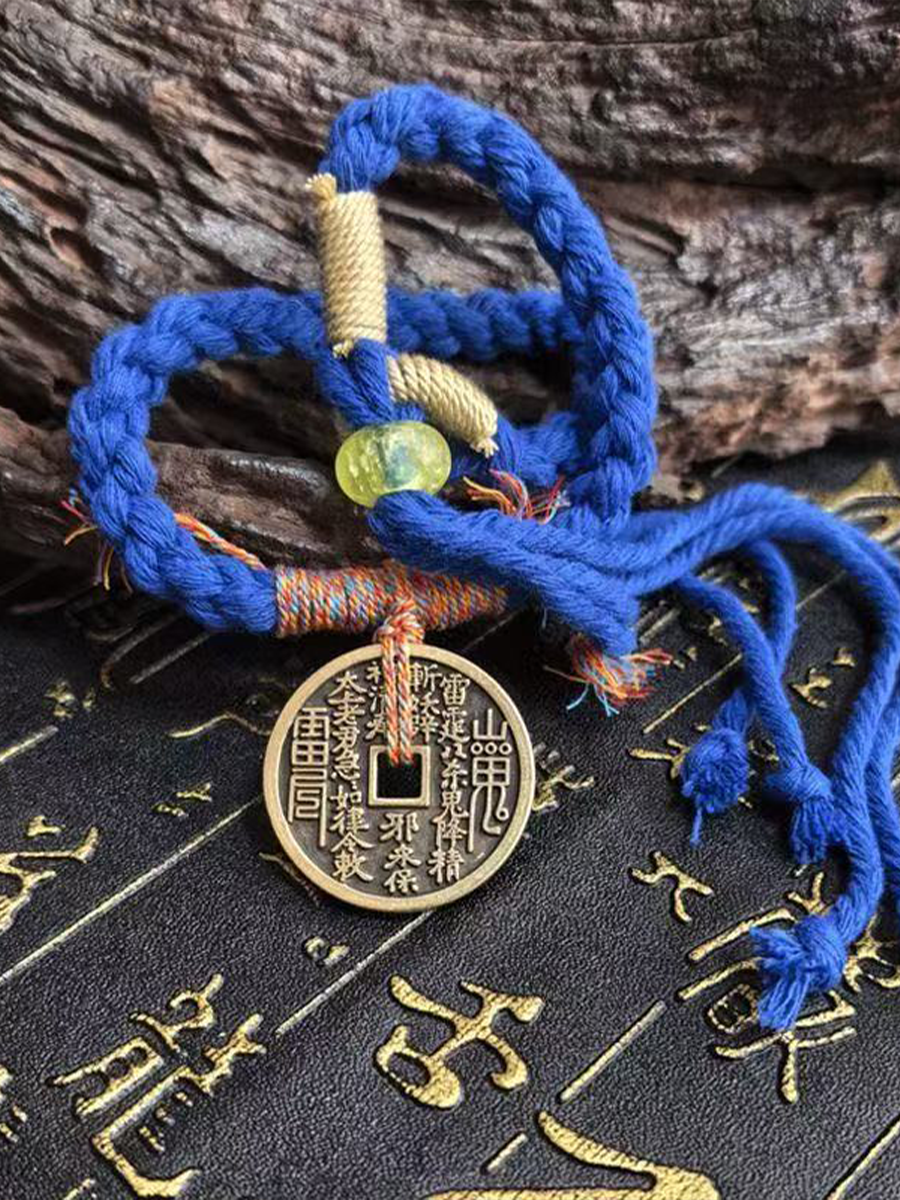 This is a blue braided rope bracelet with a Taoist mountain spirit motif.