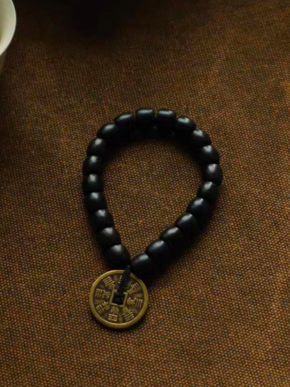 This is an ebony bracelet paired with a Taoist mountain spirit charm, displayed against a woven background.