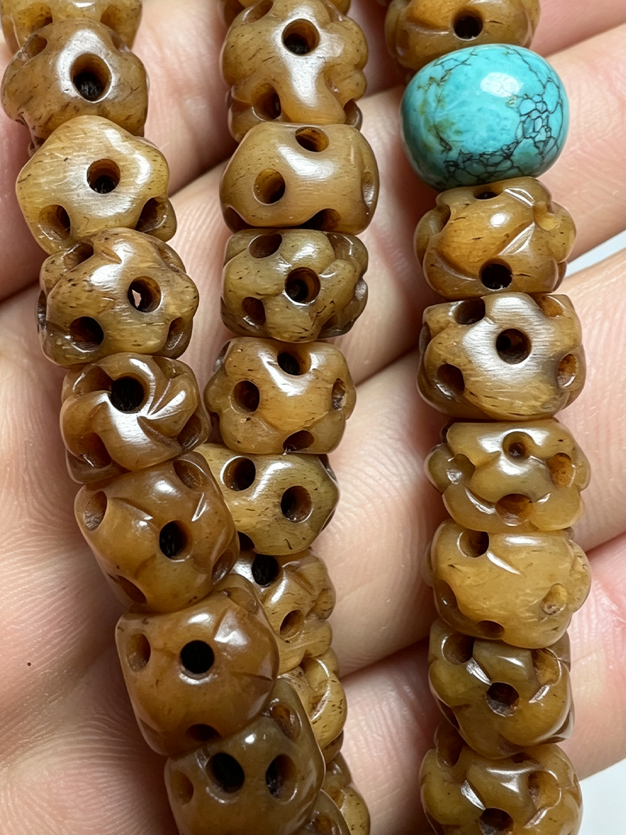 Close-up of carved brown wooden beads strung on a bracelet or necklace, held in a hand. One turquoise-blue marbled bead is visible near the top.