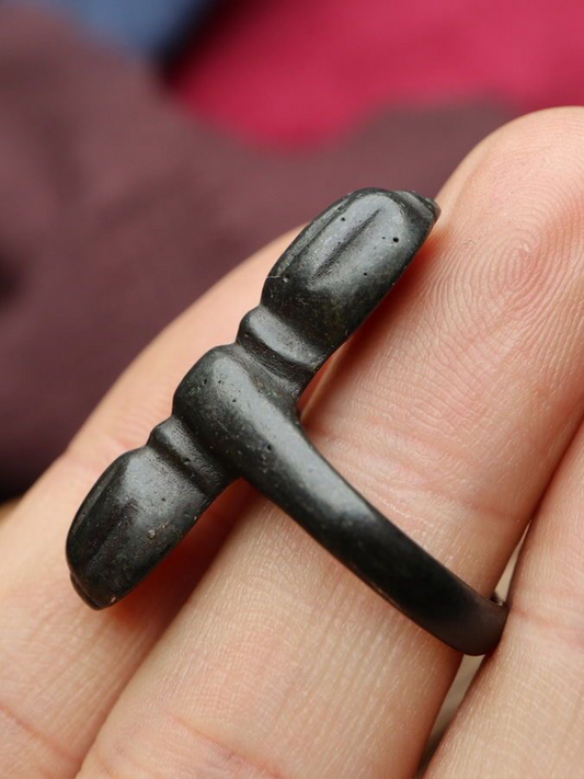A vajra (a sacred metal object) is placed on a person's finger.
