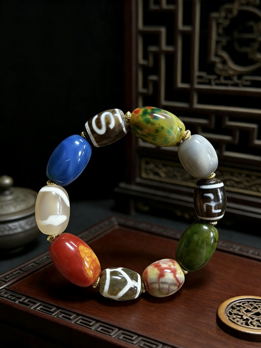 A beaded bracelet with nine distinct, polished stone beads in various colors including blue, green, red, orange, white, and brown, separated by small gold spacer rings, displayed on a dark wooden surface.