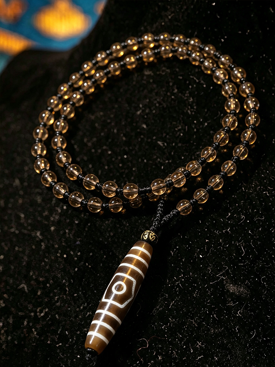 A beaded necklace with translucent brown glass beads and a carved brown and white cylindrical pendant, displayed on a black textured surface.