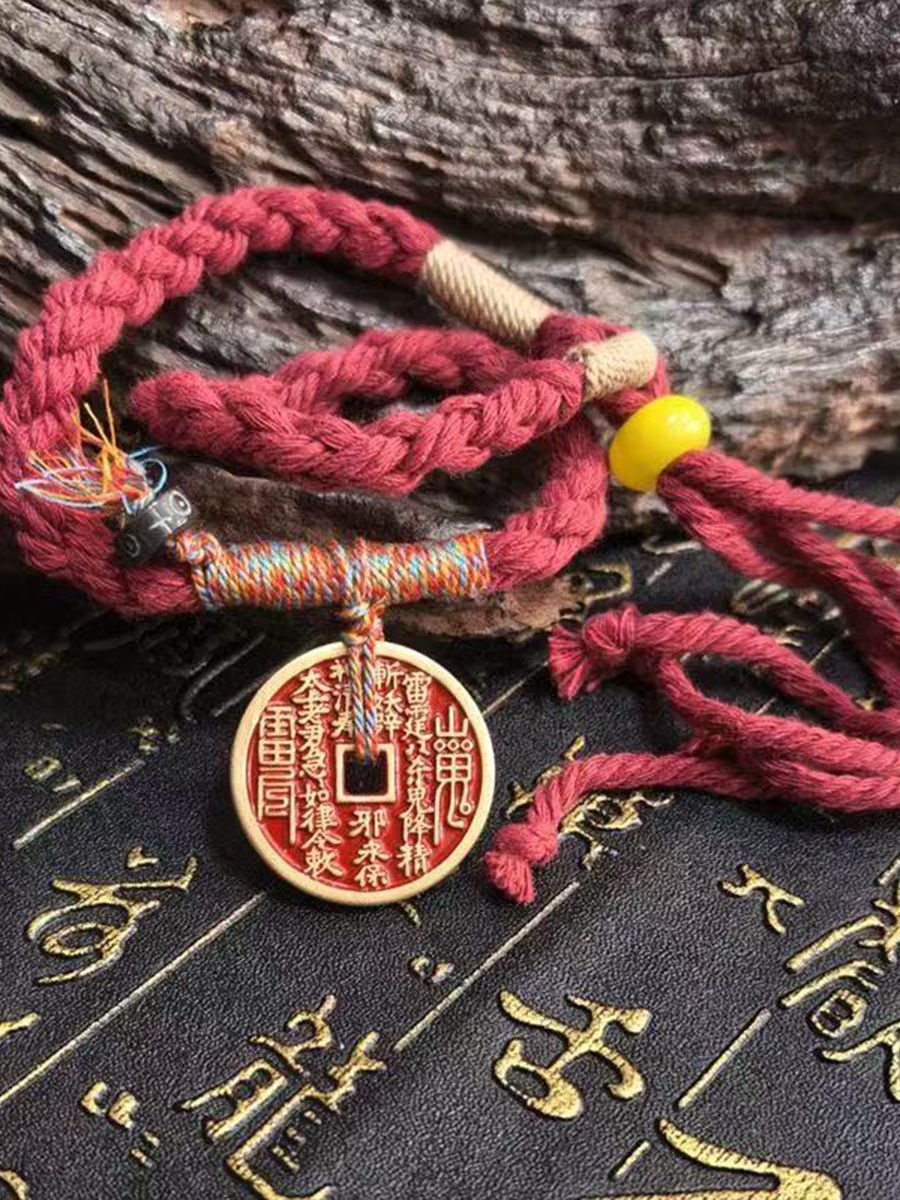 This is a red braided rope bracelet paired with a Taoist mountain spirit charm.