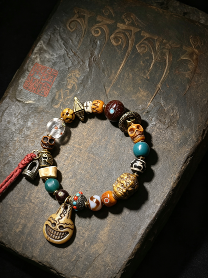 A beaded bracelet with skull, gourd, and turquoise elements, displayed on a dark textured stone surface.
