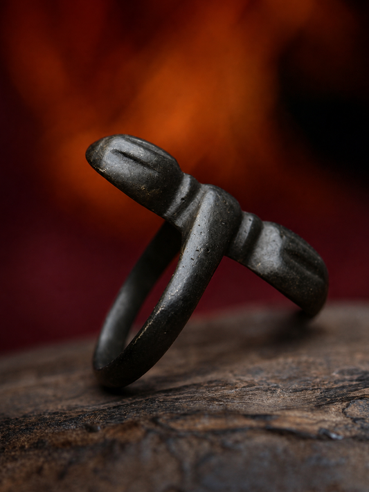 A vajra (thunderbolt) sits on a wooden display stand against a blurred reddish-orange background.