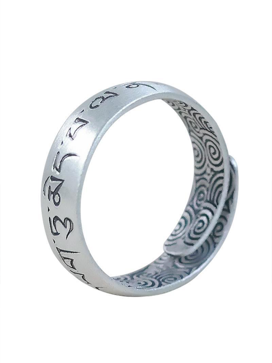 A silver-toned metal ring featuring engraved Tibetan script on the exterior and an intricate spiral pattern on the interior, shown against a plain white background.
